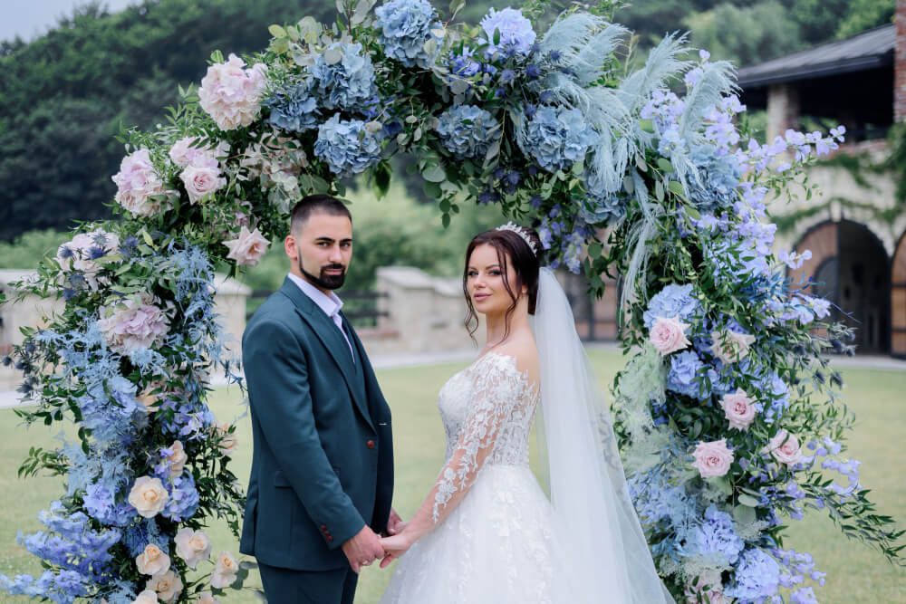 Bride and groom holding hands under a floral archway at their destination wedding.