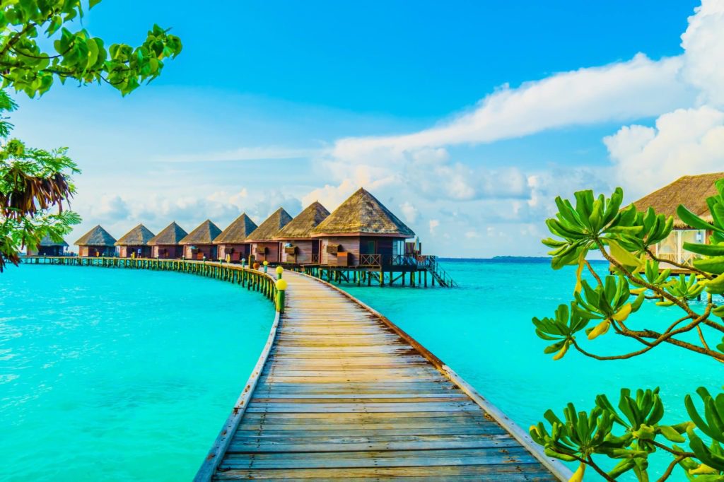 Overwater bungalows with a wooden walkway on a tropical island resort.