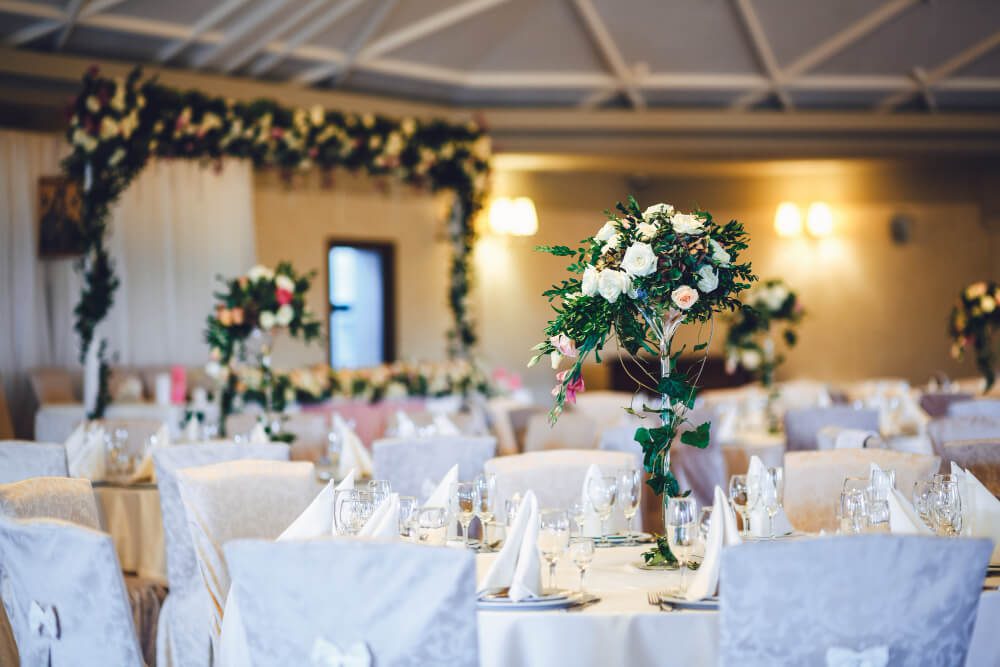 Elegantly arranged banquet hall, perfect for a destination wedding, with floral centerpieces and set tables.