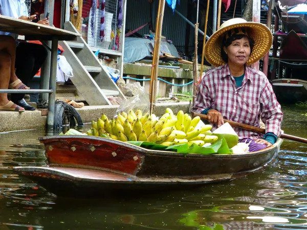 Woman vendor selling bananas in a floating market, a scene to capture when you hire a travel agent for an unforgettable journey.