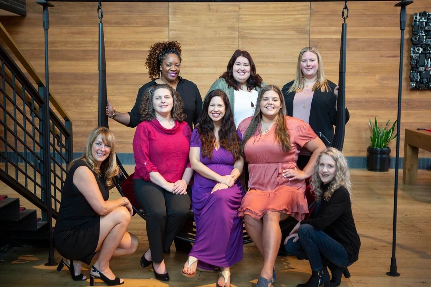 A group of smiling women posing for a photo on a staircase.