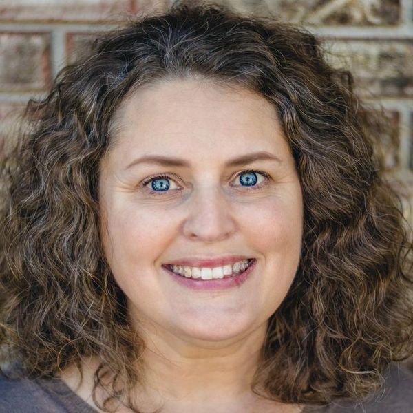 A smiling woman with curly hair and blue eyes.