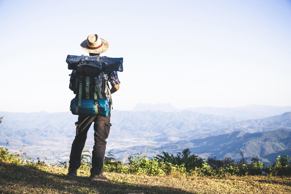 Backpacker overlooking a mountain landscape, aspiring to become a Travel Agent.