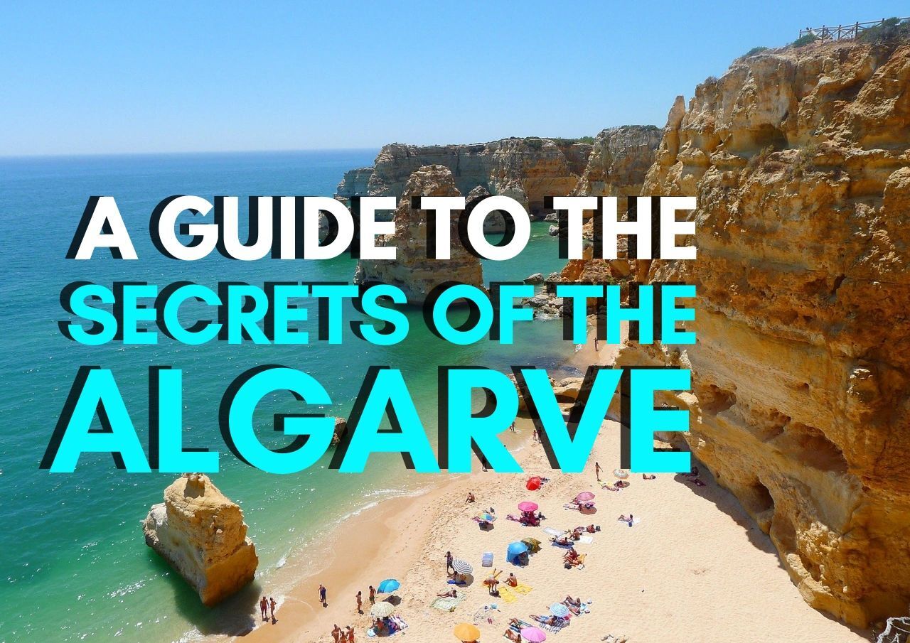 Cliff-lined beach in the algarve region with visitors sunbathing.