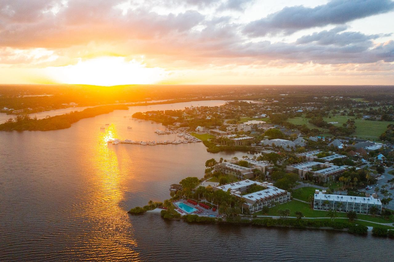 Aerial view of a coastal area during sunset with sunlight reflecting on the water.