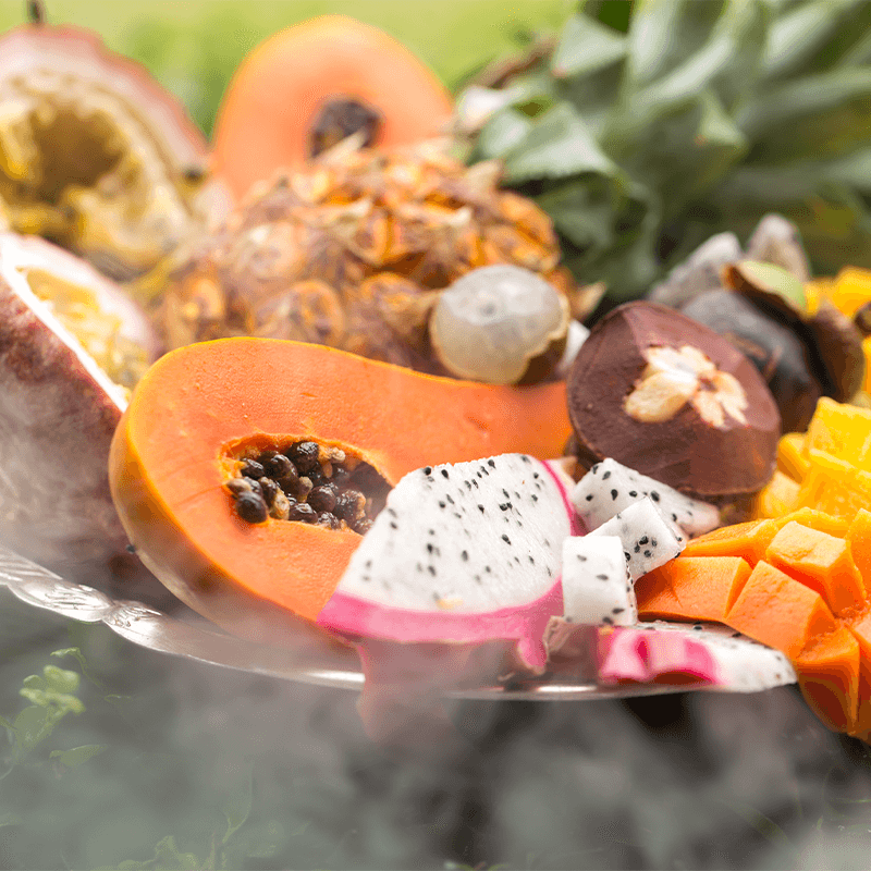 Assorted tropical fruits on display with visible steam, enticing those wondering why use a travel agent to explore exotic destinations.