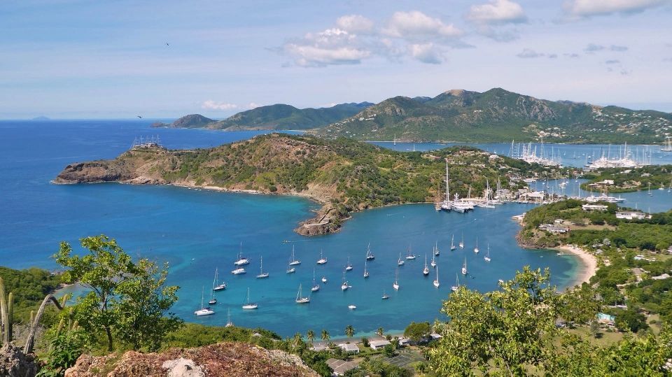 Lush greenery overlooks a serene bay dotted with yachts anchored near a coastal settlement.