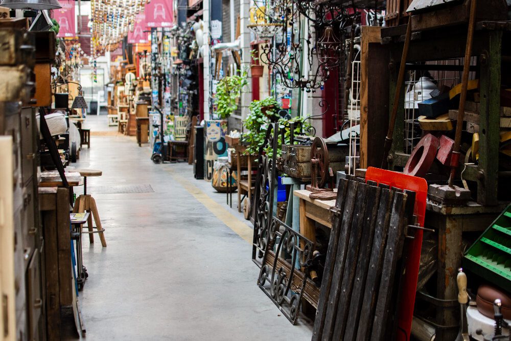 An assortment of antique items and furniture displayed along the aisles of a vintage market.