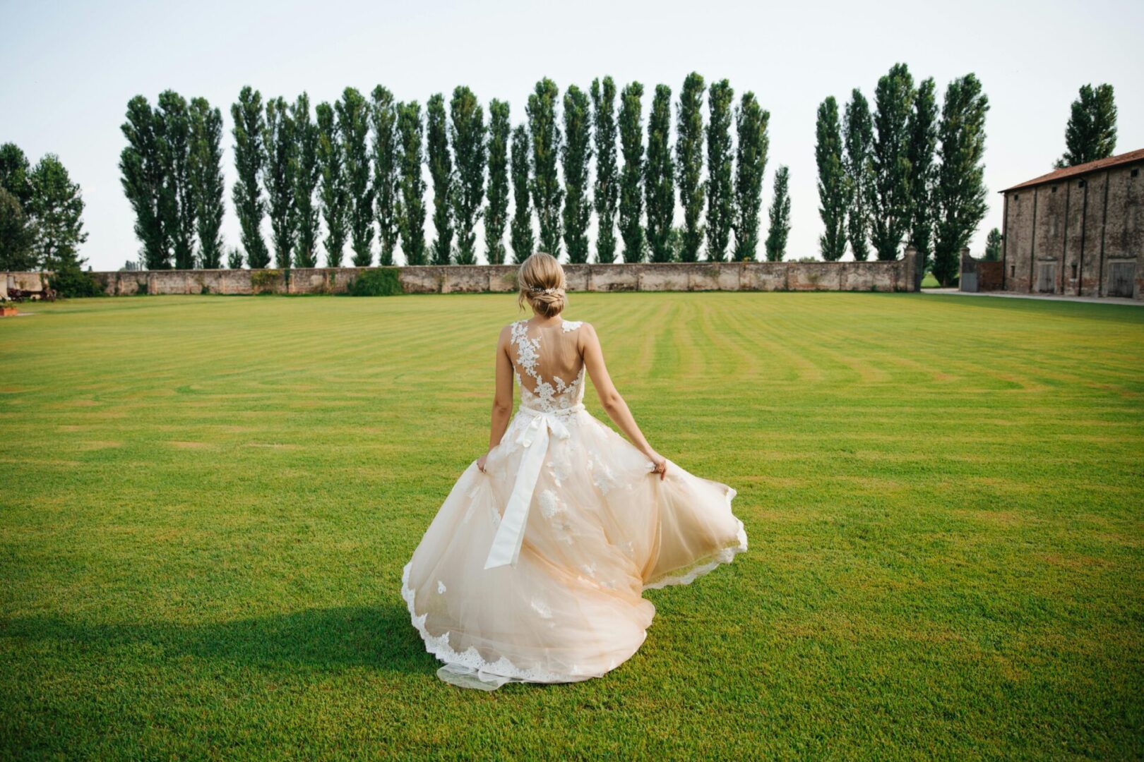 A bride in a white gown on the lawn of a villa