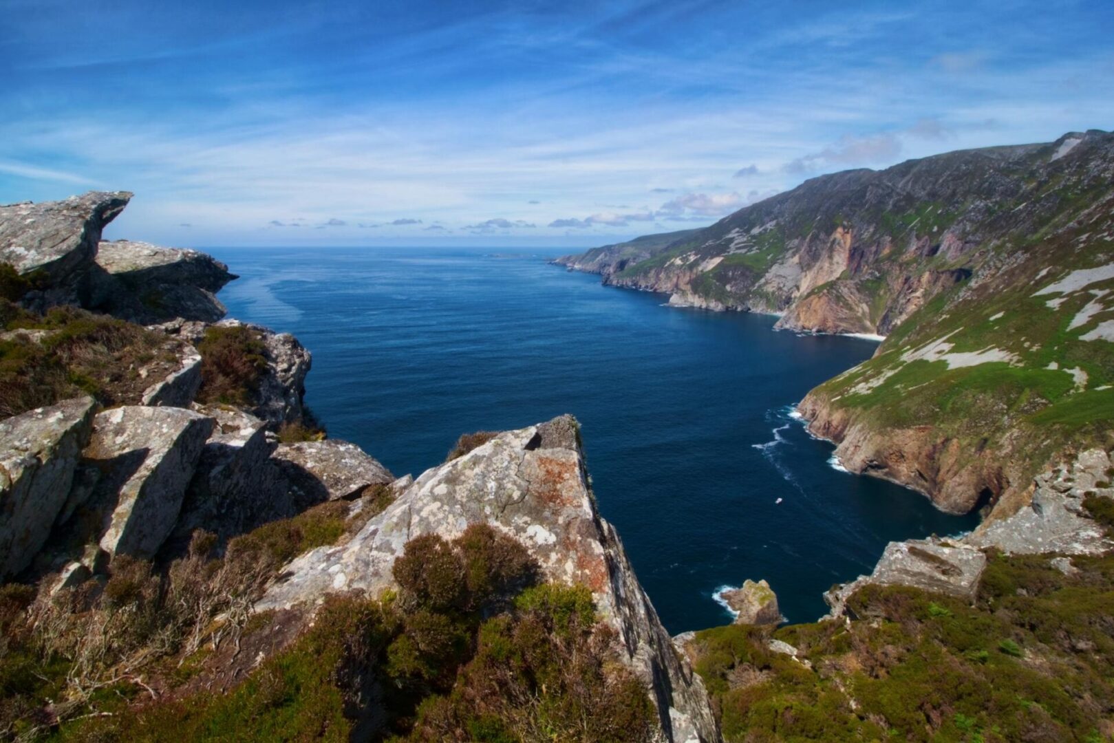 Rocky cliffs and a deep blue bay on the coast of County Donegal