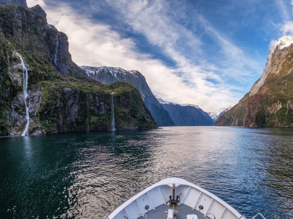 A boat cruising beneath the cliffs of Milford Sound