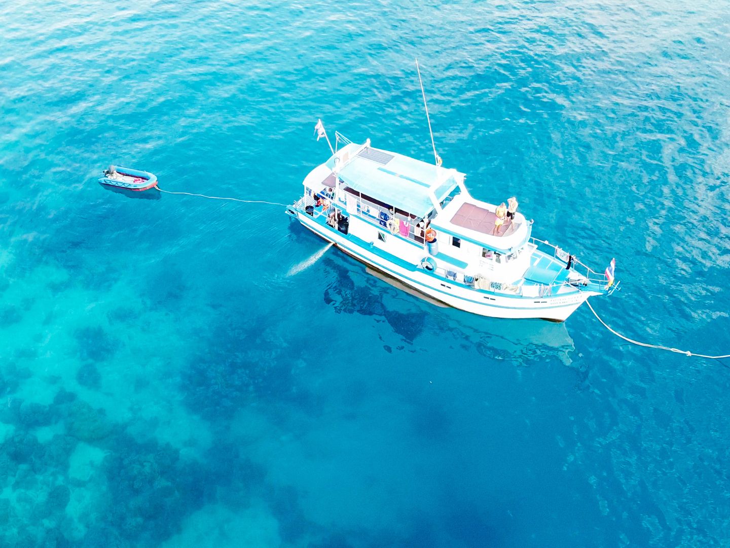 A white yacht anchored in clear turquoise Caribbean water