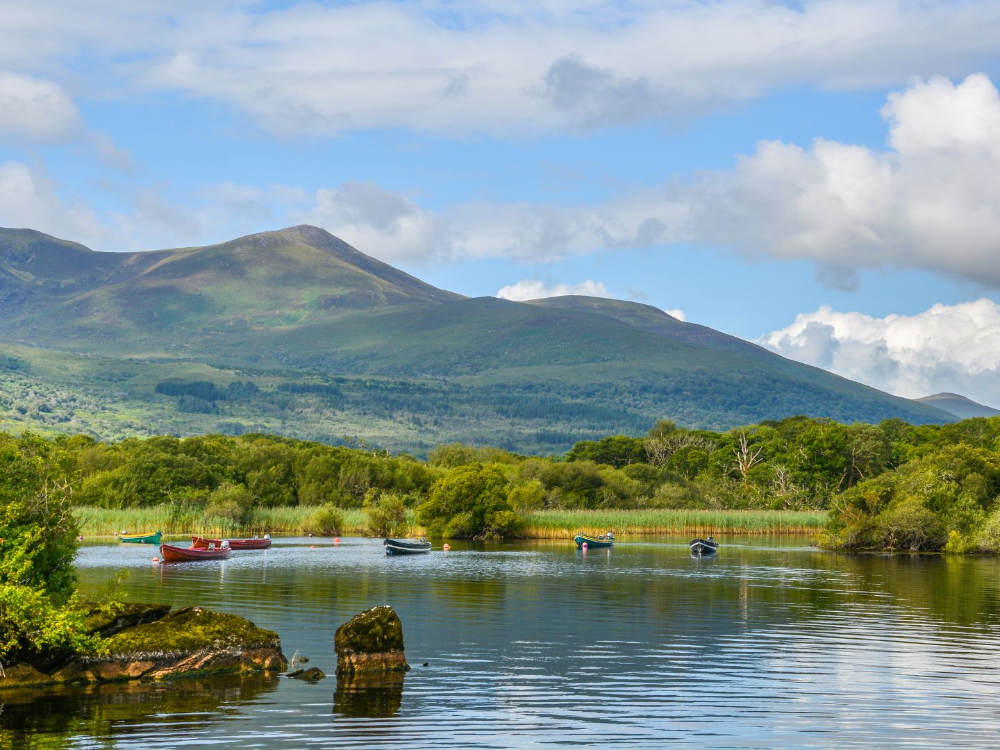 A lake in County Kerry with boats and green mountains behind