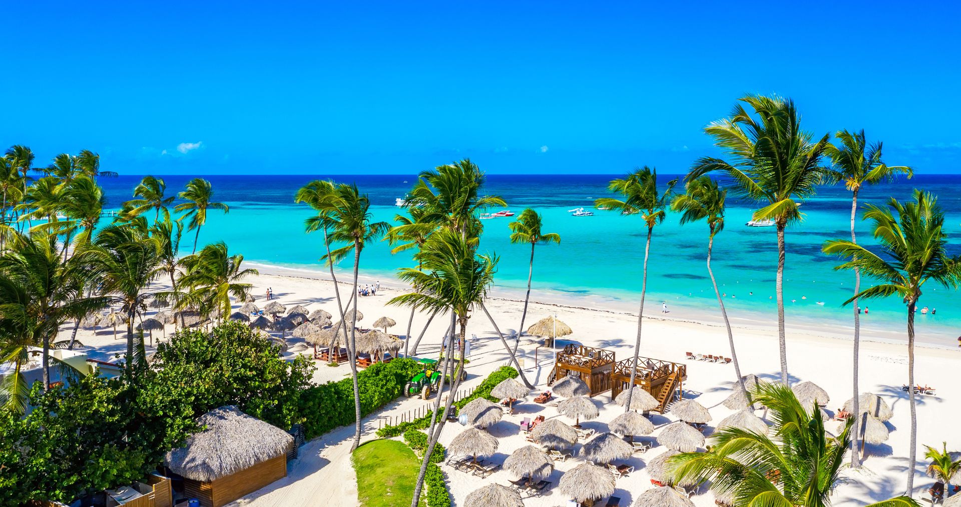 Sun loungers beneath palm trees on a white-sand beach in Punta Cana