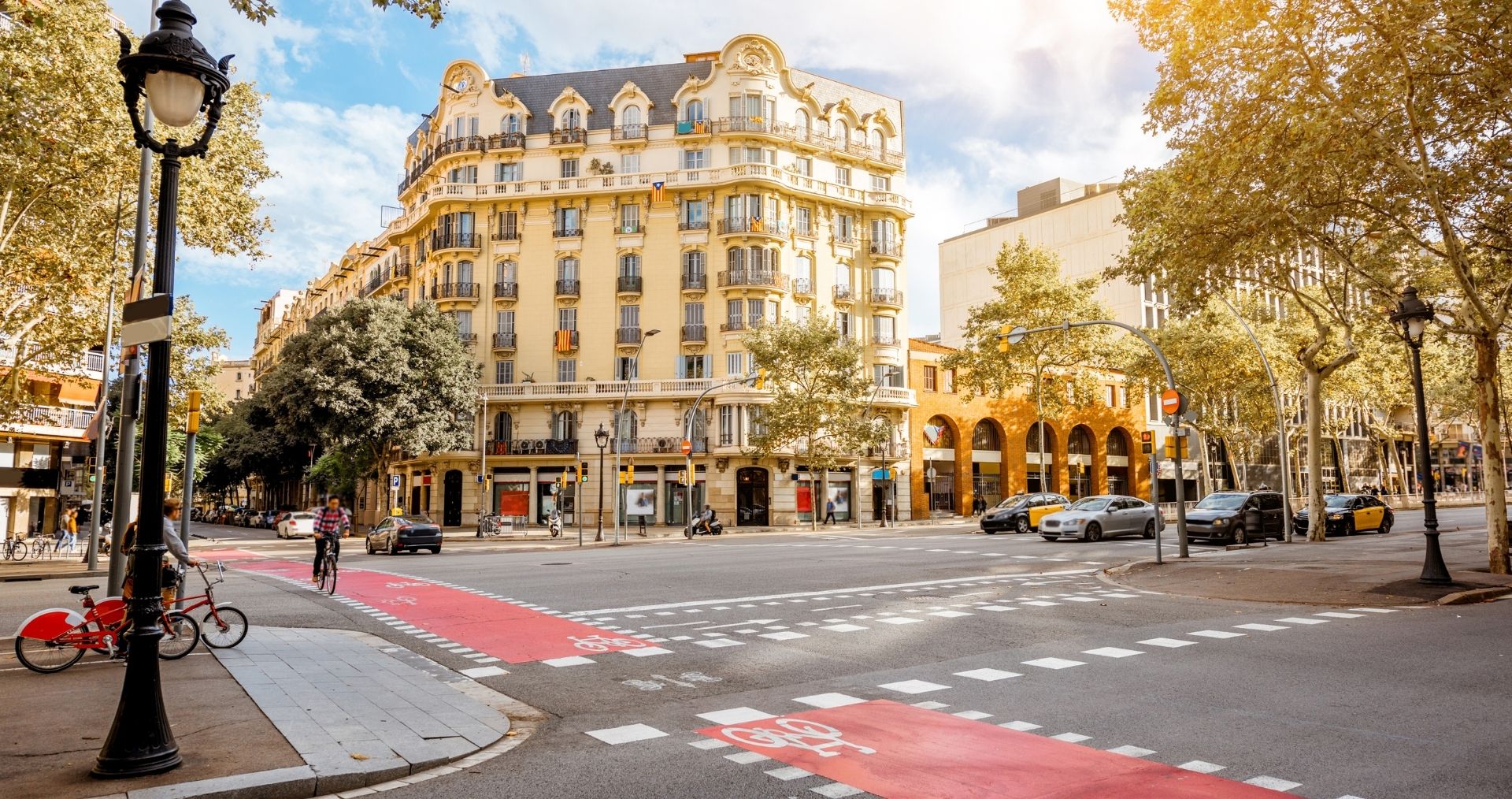 A tree-lined Barcelona street with ornate apartment buildings and a red bike lane