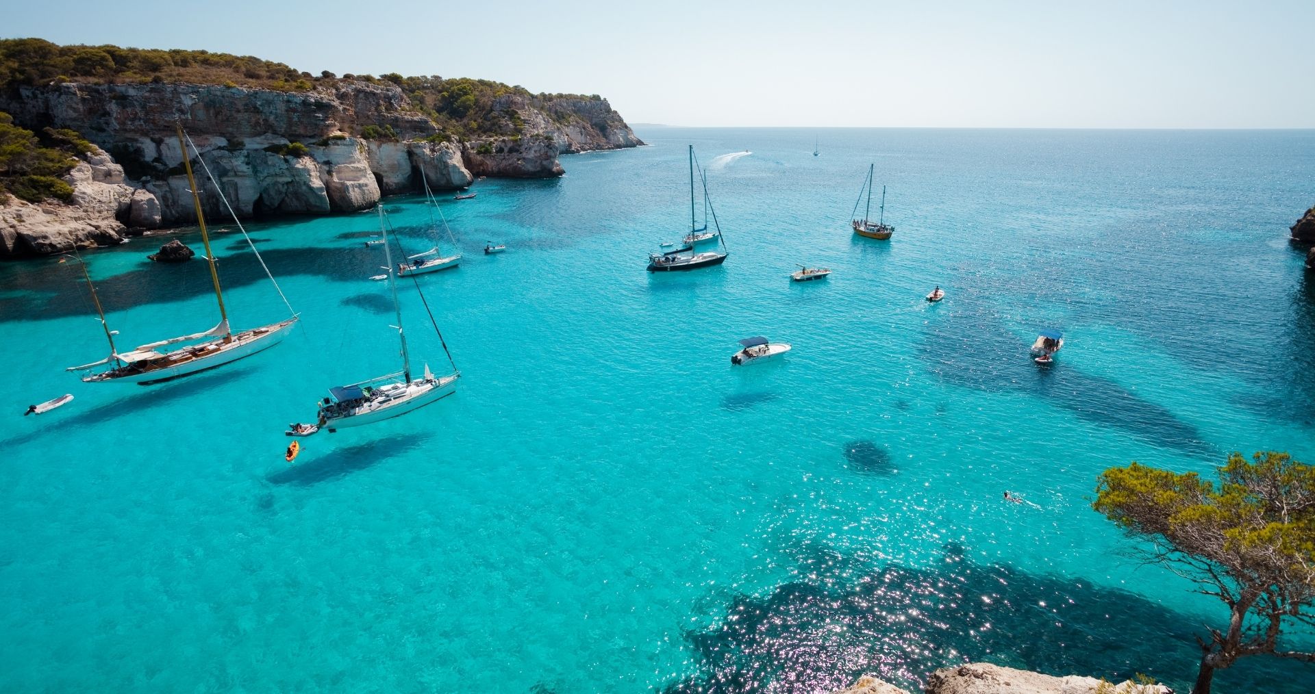 Sailboats anchored in the turquoise water of Cala Macarella, Menorca