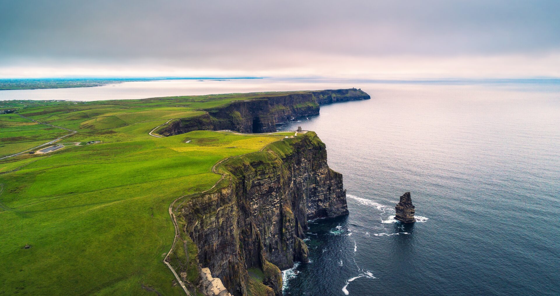 Ireland’s Atlantic sea cliffs dropping into the ocean beside a sea stack