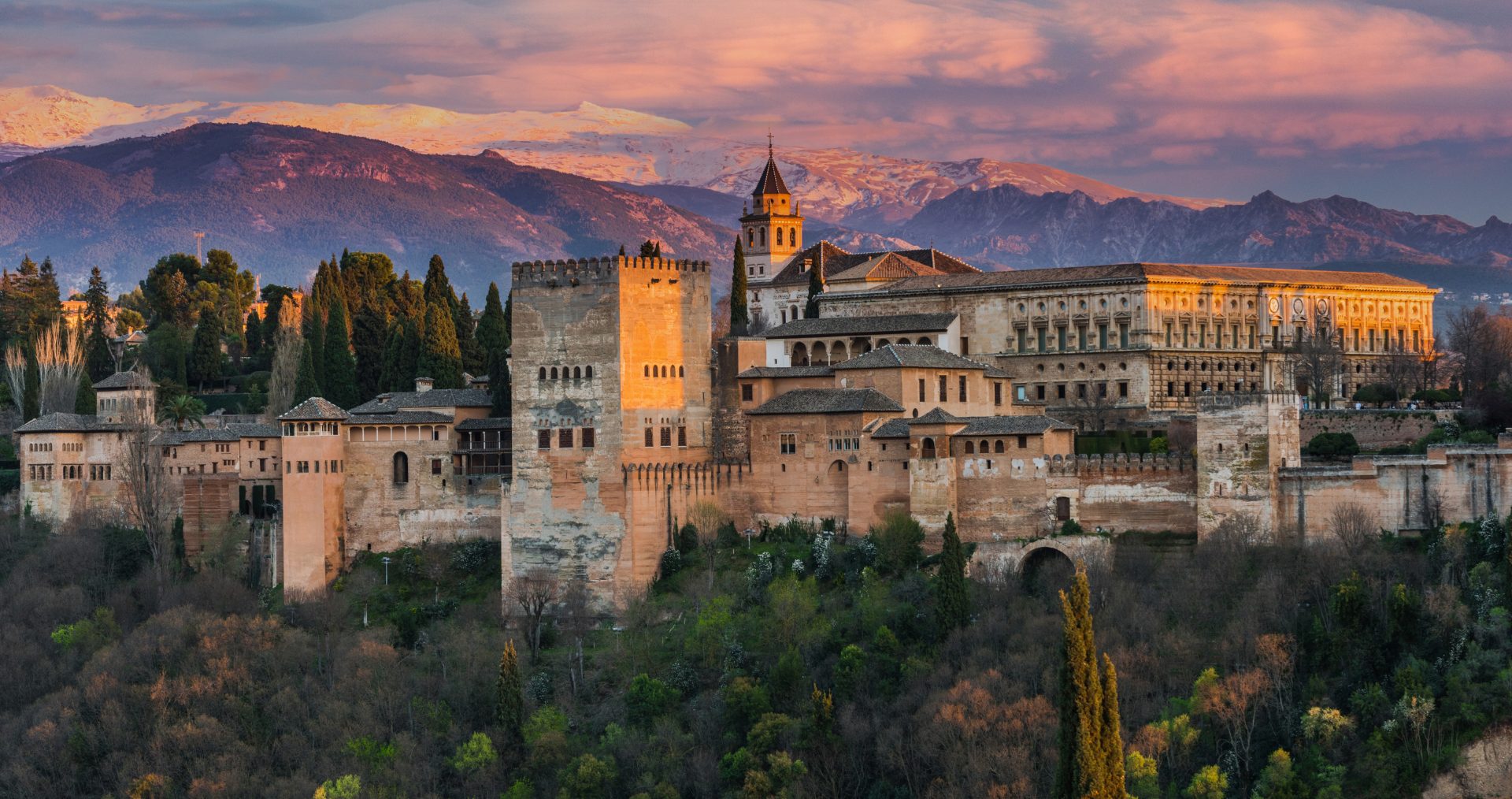 The Alhambra palace in Granada at sunset with the Sierra Nevada mountains behind