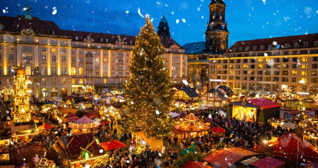A glowing Christmas market with a tall tree in a historic European square