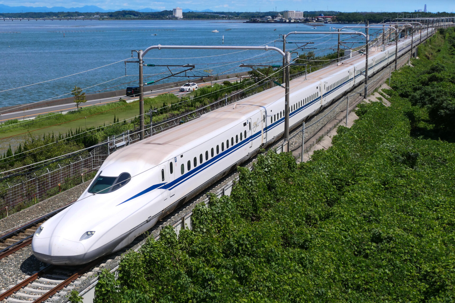 A white bullet train speeding along the coast in Japan