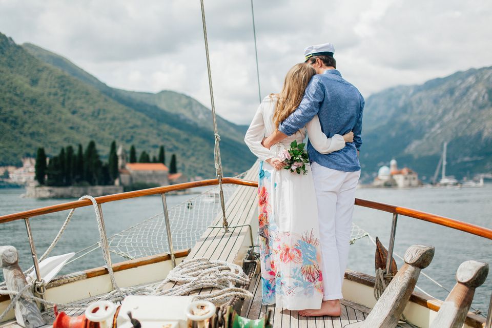 Couple embracing on a sailboat in a mountain bay