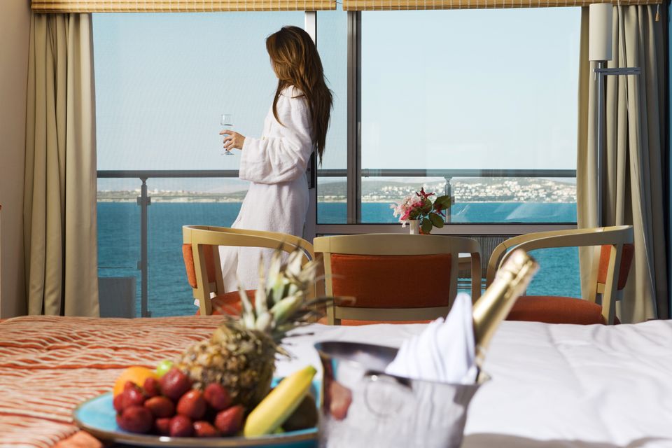 Guest in a robe enjoying an ocean-view suite with champagne