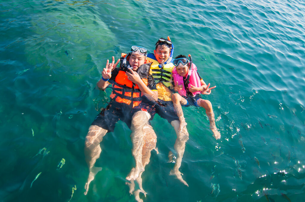family snorkeling in sea water