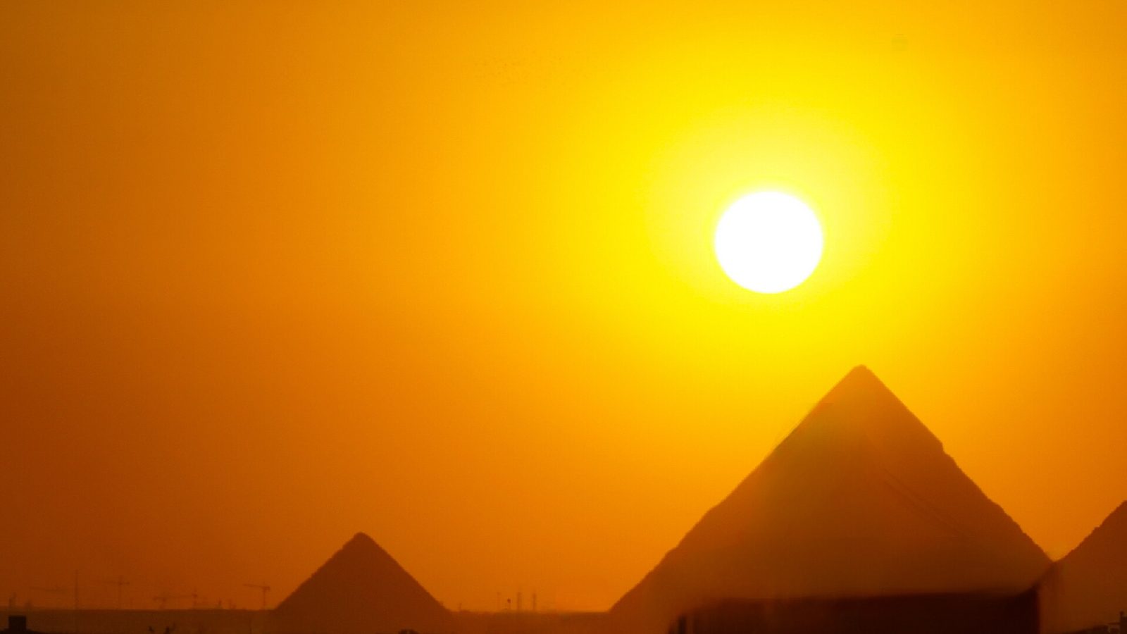 The sun setting behind the Pyramids of Giza