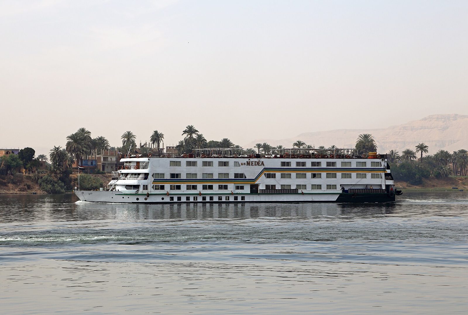 Nile cruise ship sailing past palm trees