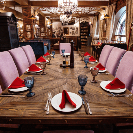 Elegant dining setup with red napkins and blue goblets on a wooden table in a vintage-style restaurant, showcasing why use a travel agent to uncover such exquisite experiences.