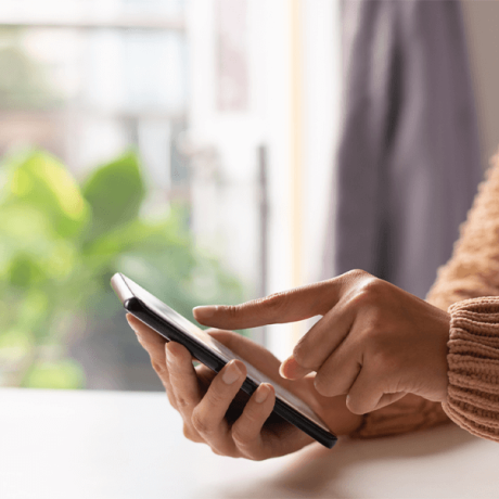 Person using a smartphone with their right hand to research "Why Use a Travel Agent" while resting their left hand on the device.